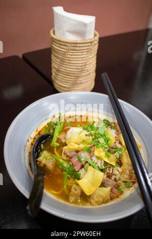 Nouilles jaunes aux œufs dans une soupe épicée de porc, photo de stock Banque D'Images