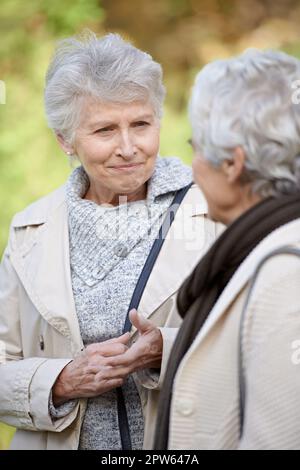 Prêter une oreille amicale. Femmes âgées souriant et écoutant un ami Banque D'Images