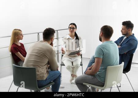 Psychothérapeute travaillant avec un groupe de personnes toxicomanes à la séance de thérapie à l'intérieur Banque D'Images