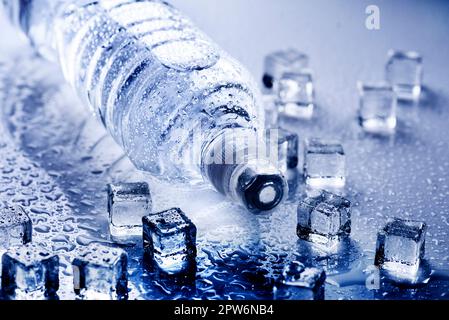 Boire de l'eau minérale fraîche en bouteille en plastique avec des cubes de glace et gouttes glacé. Concept de vie sains. Banque D'Images