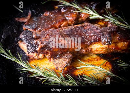 Côtes de porc grillées sauce barbecue au romarin dans un moule en verre. Banque D'Images