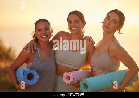 Portrait des femmes de yoga liant, tenant des tapis de yoga en pratique en plein air dans la nature éloignée. Groupe diversifié de jeunes amis actifs souriants debout ensemble Banque D'Images