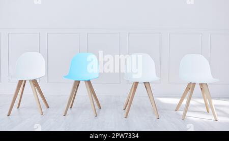 Quatre chaises alignées dans une salle d'attente de bureau. Un président bleu et trois blancs, attendant que des candidats potentiels soient assis, interviewés et marmite Banque D'Images