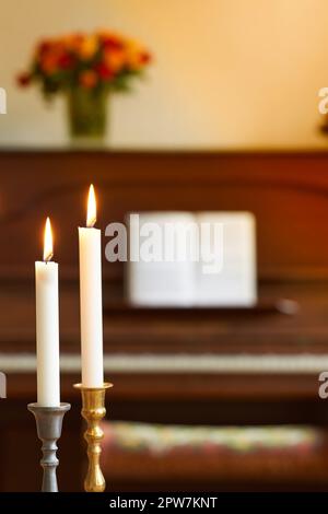 Deux bougies fines dans les supports de bâton de bougie brûlant contre le piano flou et le fond de bouquet de fleurs. Photophores élégantes en or et argent Banque D'Images