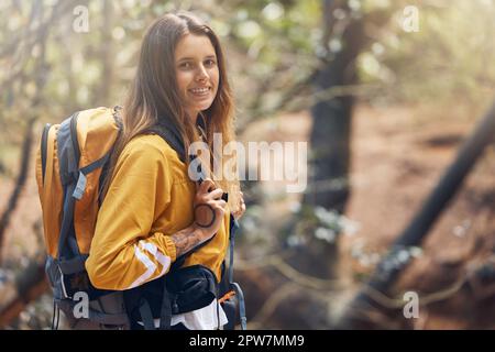 Une jeune femme caucasienne active portant un sac à dos tout en faisant de la randonnée dans la forêt. Jeune femme brunette marchant seule dans les bois. Elle aime être Banque D'Images