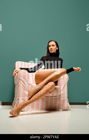 Belle femme de course mixte dans des collants avec motif à pois assis dans un fauteuil Banque D'Images