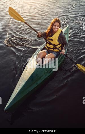 Pour nourrir ma faim aventureuse, je vais faire du kayak. Photo en grand angle d'une belle jeune femme en kayak sur un lac à l'extérieur. Banque D'Images