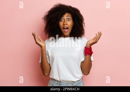 Grand jour de ventes, la femme a ouvert ses yeux et la bouche dans une énorme surprise, bras un côté, sur fond rose. Photo de haute qualité Banque D'Images