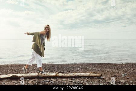 Faire des souvenirs en solo au lac. une jeune femme marchant le long d'une bûche à un lac. Banque D'Images