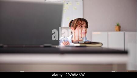 Femme ébatiée se cachent derrière la chaise et sous le bureau Banque D'Images