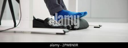 Homme utilisant un repose-pied pour réduire la tension du dos et la fatigue des pieds Banque D'Images