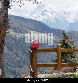 Boîte aux lettres rouge sur une clôture en bois dans la ville alpine de Lignan dans l'Aoste Vally, au nord-ouest de l'Italie Banque D'Images