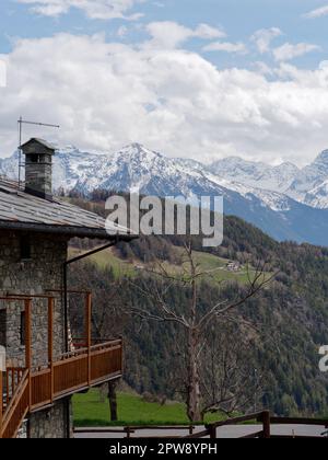 Propriété dans la ville alpine de Lignan dans l'Aoste Vally, NW Italie. Montagnes enneigées iet une forêt de l'autre côté de la vallée au printemps Banque D'Images