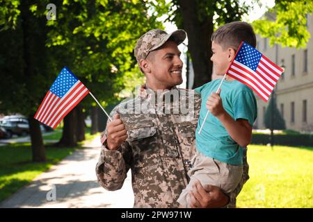 Soldat et son petit fils avec drapeaux américains à l'extérieur. Fête des anciens combattants aux États-Unis Banque D'Images