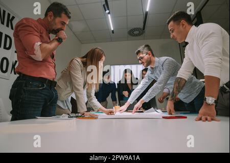 Les gens d'affaires qui ont une commotion en se tenant au-dessus de la table d'affaires à l'espace de travail commun Banque D'Images