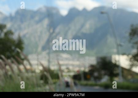 Route près de la ville et des grandes montagnes, vue floue Banque D'Images