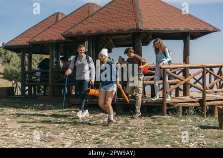 Quatre randonneurs marchent loin du banc en bois Banque D'Images