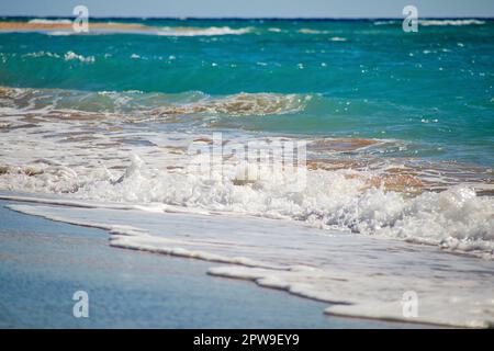 Les vagues frappent doucement la plage de sable en créant un magnifique jet de la belle eau turquoise azur Banque D'Images