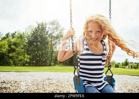 Rejoignez-nous ou vous ne serez pas à court de plaisir. Portrait d'une jeune fille jouant sur une balançoire au parc. Banque D'Images