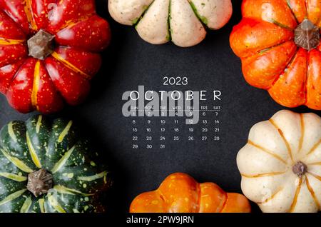 Octobre 2023 Calendrier et citrouilles sur fond de carton noir. Banque D'Images