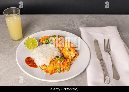 Délicieux Moqueca de poisson brésilien avec tomate, oignon, huile d'olive, coriandre et graines d'orocum. Servi sur une assiette en porcelaine blanche avec du riz. Avec noix de cajou ju Banque D'Images