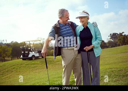 Vous êtes très bien. un couple senior souriant appréciant une journée sur le parcours de golf. Banque D'Images