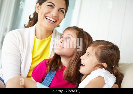 Leur raconter des histoires de quand elle était enfant. Deux filles heureuses passent du temps de qualité avec leur mère. Banque D'Images