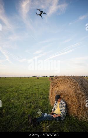 Agriculteur avec ordinateur portable et drone sur le terrain. Agriculture intelligente et numérisation agricole. Banque D'Images