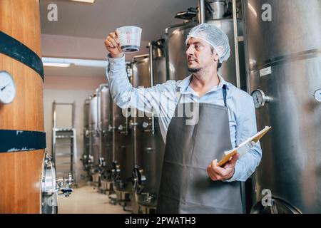 Viticulteur travaillant dans une grande usine moderne de vins alcool industrie de boisson qualité et contrôle de fermentation Banque D'Images