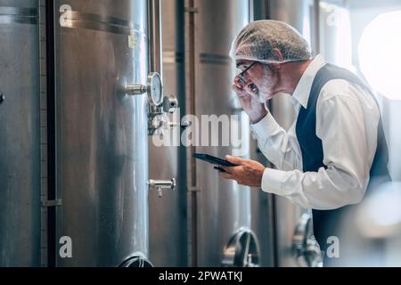 Viticulteur travaillant dans une grande usine moderne de vins alcool industrie de boisson qualité et contrôle de fermentation Banque D'Images