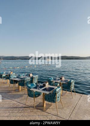 Des tables avec des chaises dans un café de rue se tiennent sur un quai au bord de la mer Banque D'Images