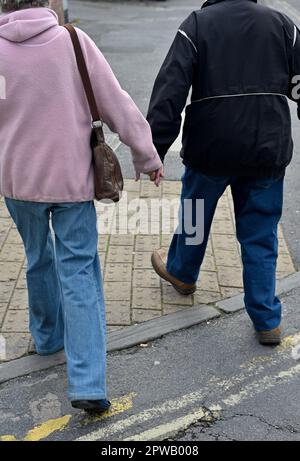 Un couple plus âgé s'éloigne le long de la route, de la chaussée et tient les mains Banque D'Images