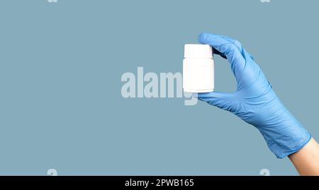 Main tenant des pilules bocal maquette sur fond bleu de bannière médicale. Banque D'Images