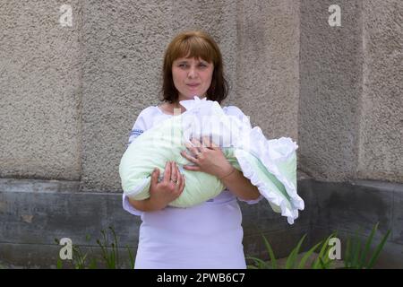 Jolie femme tenant un bébé nouveau-né dans ses bras Banque D'Images