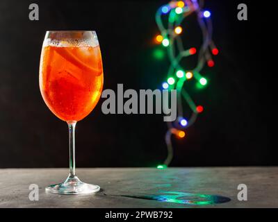 Verre d'Aperol Spritz cocktail sur un fond flou avec des lumières colorées. Apéritif Spritz cocktail sur la table de fête. Copier l'espace Banque D'Images