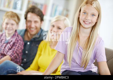 Shes la princesse familiale. Portrait d'une petite fille assise avec sa famille sur un canapé. Banque D'Images