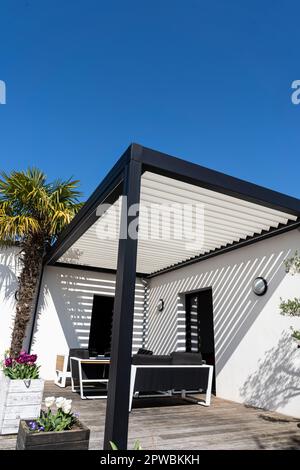 éco-respectueux bioclimatique aluminium pergola structure d'ombre, auvent et terrasse toit, salon de jardin, chaises, barbecue en métal entouré par l'aménagement paysager Banque D'Images