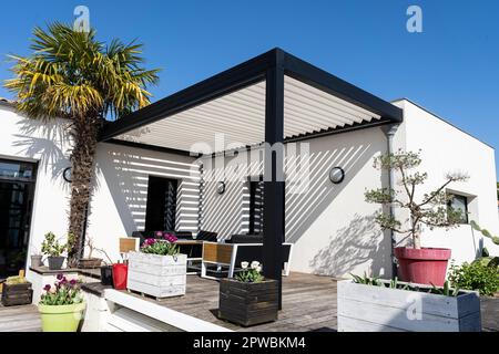 éco-respectueux bioclimatique aluminium pergola structure d'ombre, auvent et terrasse toit, salon de jardin, chaises, barbecue en métal entouré par l'aménagement paysager Banque D'Images