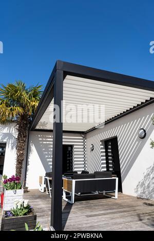 éco-respectueux bioclimatique aluminium pergola structure d'ombre, auvent et terrasse toit, salon de jardin, chaises, barbecue en métal entouré par l'aménagement paysager Banque D'Images