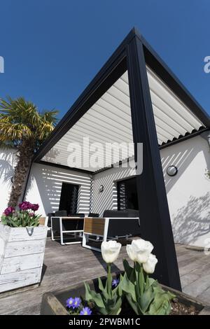 éco-respectueux bioclimatique aluminium pergola structure d'ombre, auvent et terrasse toit, salon de jardin, chaises, barbecue en métal entouré par l'aménagement paysager Banque D'Images