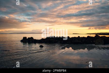 Magnifique coucher de soleil paysage marin avec des rochers sur la plage de sable de Salthill à Galway, Irlande Banque D'Images