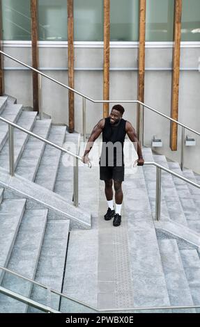 Assuré et heureux tenue sportive jeune homme noir debout à l'extérieur. Banque D'Images
