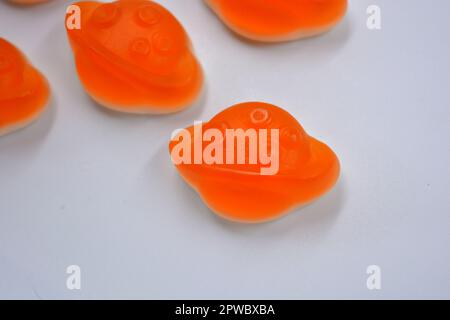 Bonbons colorés et colorés pour enfants en gelée, bonbons sous forme de planètes orange, astéroïde, jupiter situé sur un fond blanc. Banque D'Images