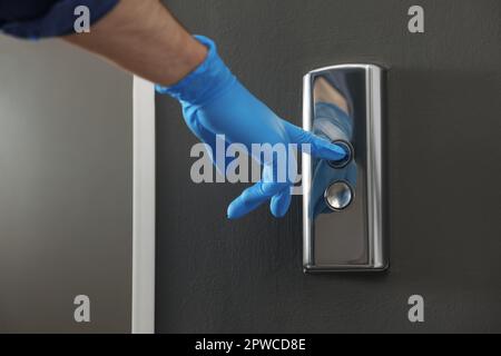 Homme dans le gant en appuyant sur le bouton d'appel de l'ascenseur, gros plan. Mesure de protection Banque D'Images