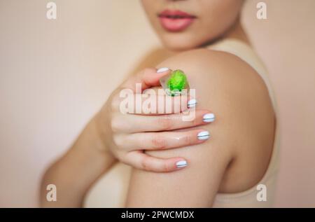 Récolte femelle non reconnaissable avec pile de glaçons avec herbes pour les soins de beauté en studio Banque D'Images