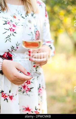 Femme méconnue en robe fleurie au vin blanc le jour d'été ensoleillé dans la nature Banque D'Images