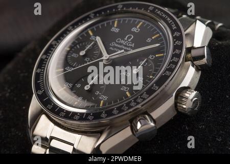 Milan, Italie - 28 avril 2023: Gros plan sur un vintage Omega Speedmaster automatique de luxe montre de poignet, l'arrière-plan est une texture de roche floue. Banque D'Images