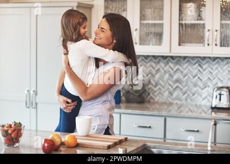 Je n'arrête jamais de vous aimer. une mère heureuse embrassant sa petite fille mignonne dans la cuisine à la maison. Banque D'Images