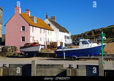 Bateaux de pêche dans un quai sec avec de jolis cottages en bord de mer à l'arrière, West Bay, Dorset, Royaume-Uni, Europe. Banque D'Images