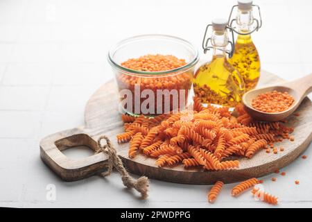 Pâtes de lentilles rouges fusilli sur fond de béton gris. Bol avec pâtes crues et lentilles rouges. Pâtes sans gluten. Banque D'Images